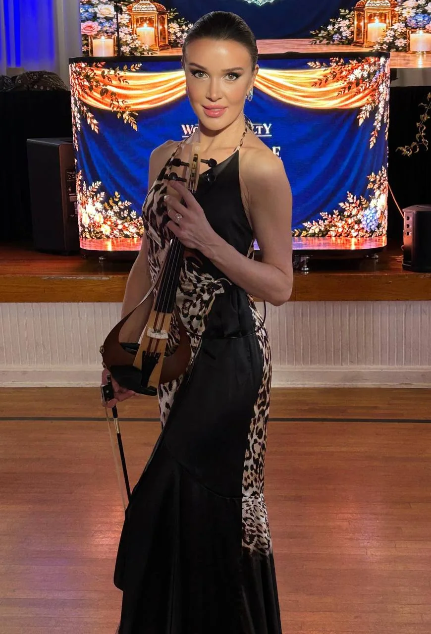 Anna Cordin holding her violin in a floor-length black and leopard-print gown