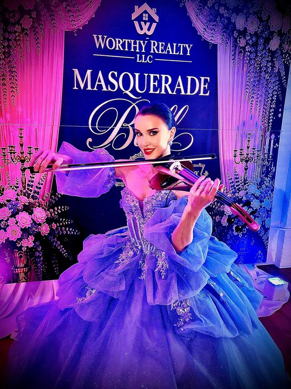 Anna Cordin playing electric violin in a lavender ball gown at a masquerade event