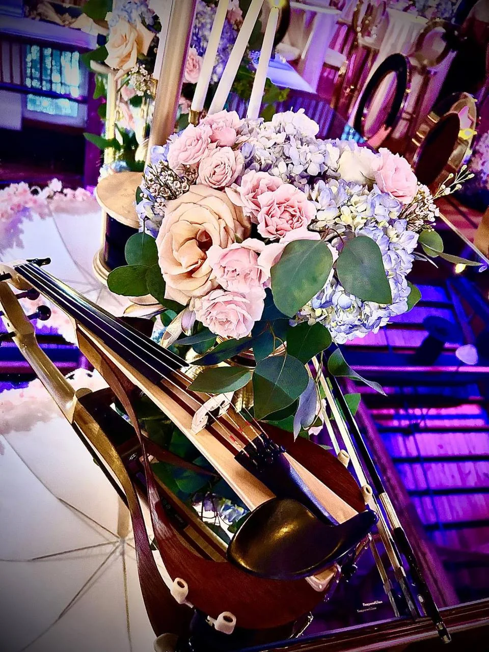 Violin and bow beside pastel roses and hydrangeas, ready for a live performance