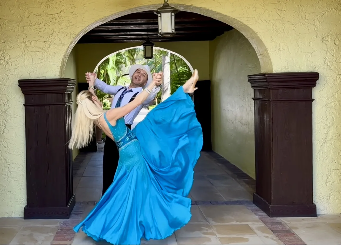 Anna and Grigol dancing ballroom beneath a Spanish-style archway